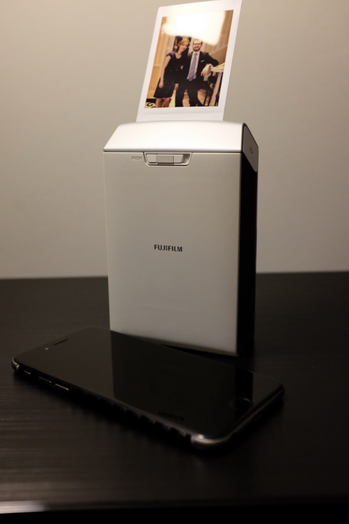 The Fujifilm Instax SP-2 printer with a sample photo of myself and my wife, with my iPhone 6 adjacent for size comaprison.